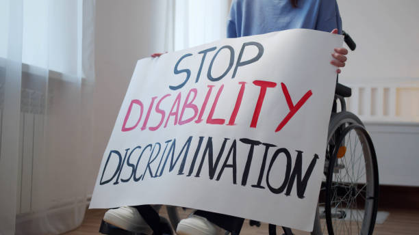 persona disabile con cartello stop disability discrimination( stop all'abilismo)