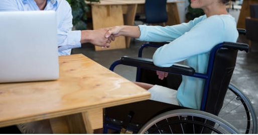 persona disabile in carrozzina strnge la mano al suo datore di lavoro